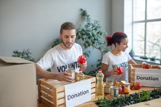 Two young people sorting food in a donation box