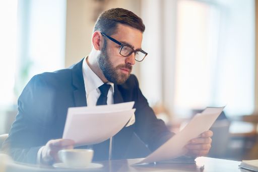 Confident banker reading financial papers while sitting in cafe