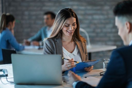 Young happy businesswoman reading reports while going through paperwork and working with a colleague in the office.