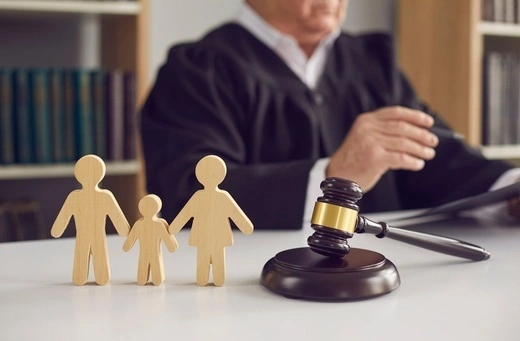 Wooden family figures beside a judge’s gavel, representing custody agreements, child support, and visitation rights.
